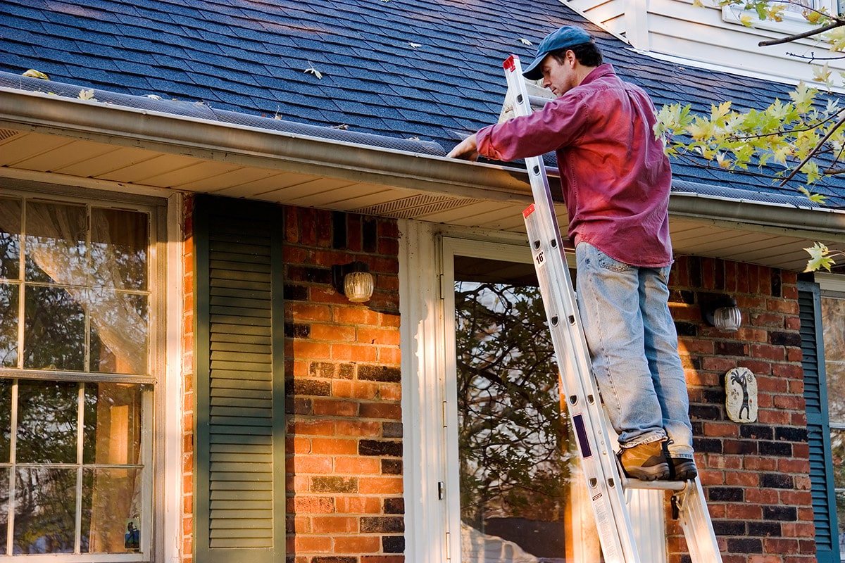 man cleaning house gutters